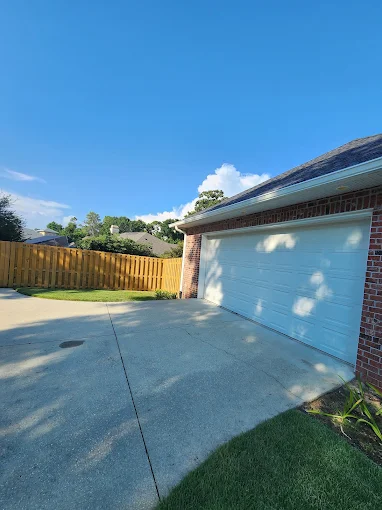 White gutter and downspout installed along the roof edge of a residential garage.