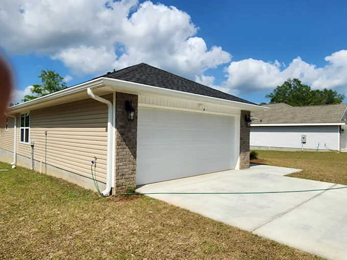 Completed white gutter system around a residential garage roofline.