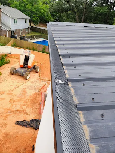 Close view of a gutter system installed along the edge of a metal roof.